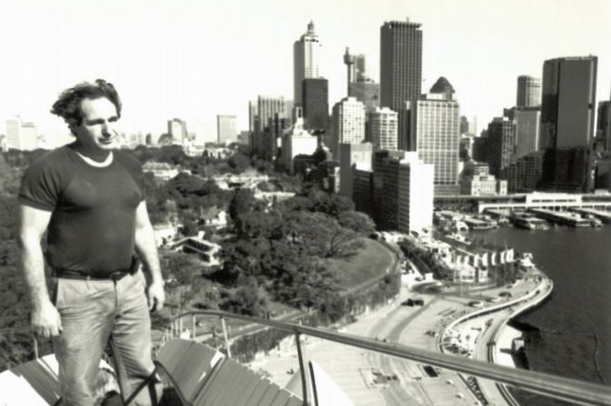 Black and white photo of Steve Tsoukalas standing on the Sydney Opera House sails