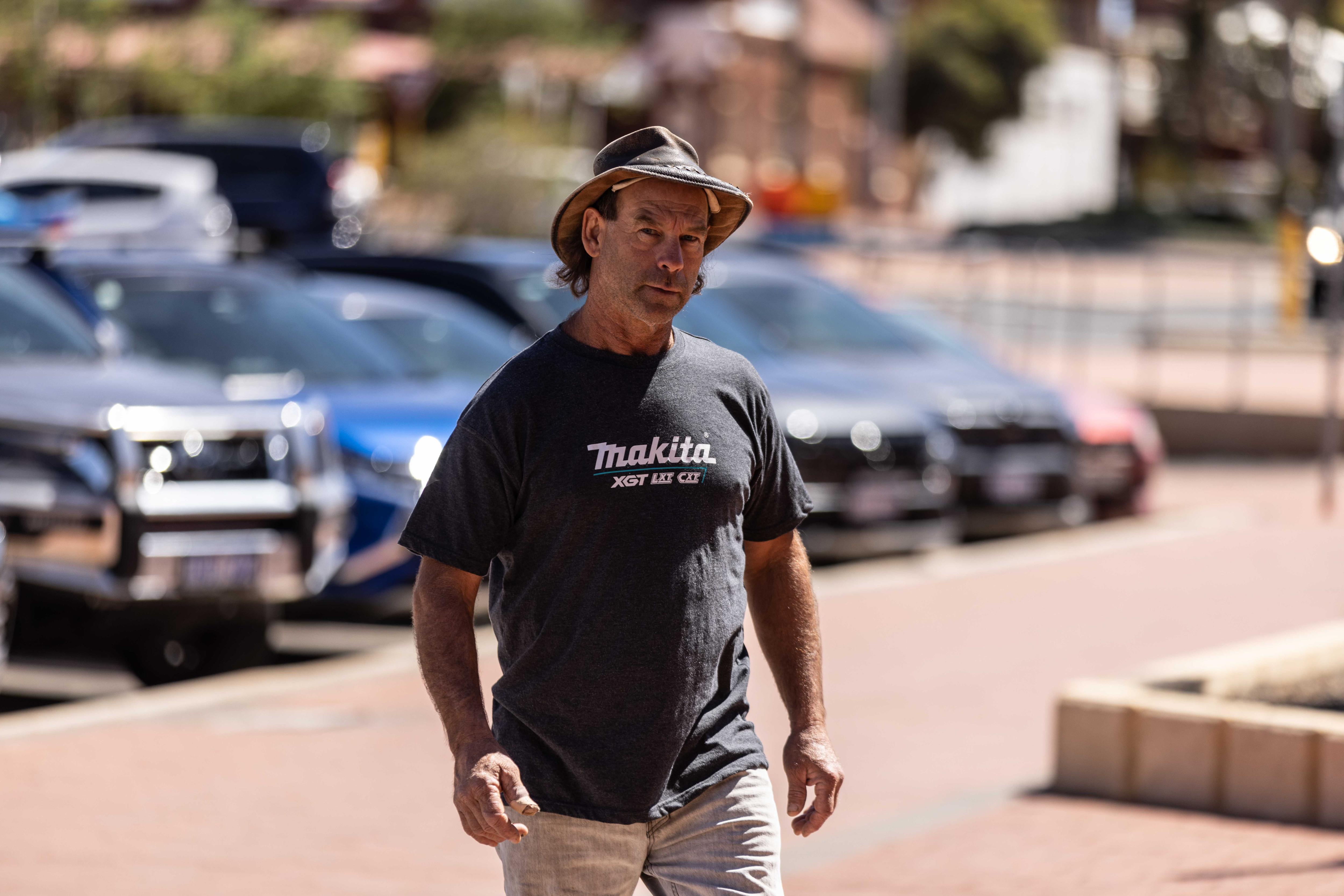 A man wearing a wide-brim hat walks into a police station to report for bail for court trial.  