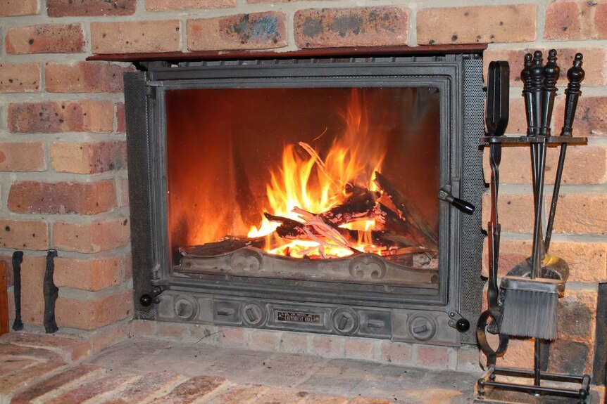 A fire burns in a brick fireplace in a home.