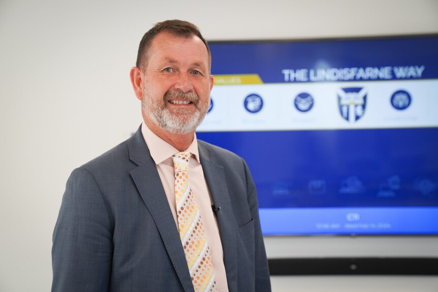 Principal Stuart Marquardt in front of a screen that says "the Lindisfarne way".