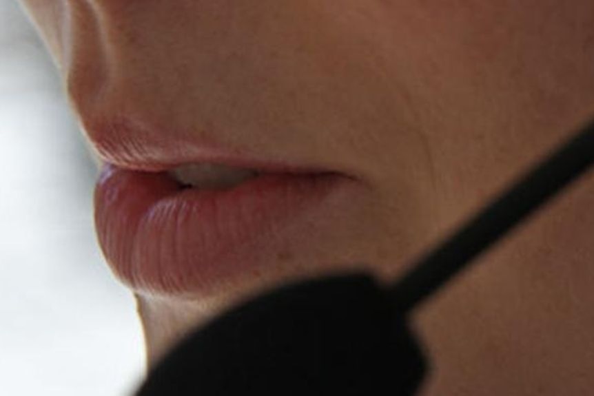 A close up of a woman's mouth with a microphone belonging to a headset.