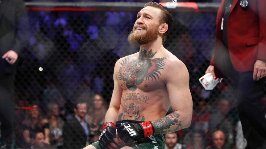 Conor McGregor smiles while kneeling on the octagon floor after defeating Cowboy Cerrone in UFC 246