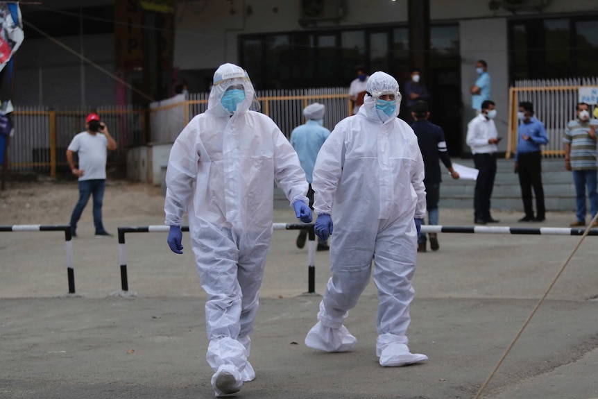 People wearing protective gear walk towards a train station.