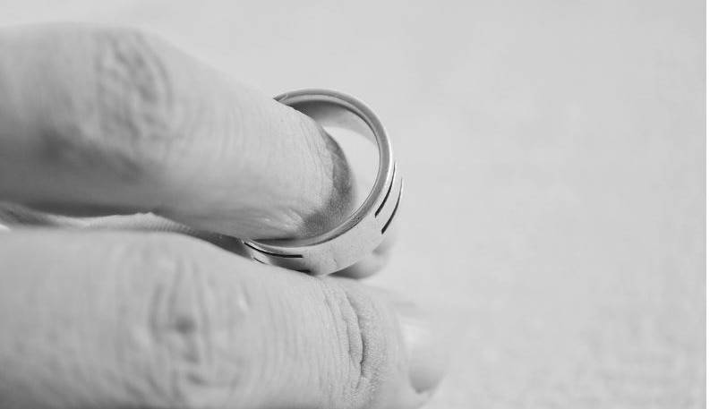 Black and white picture of a hand holding a wedding ring 