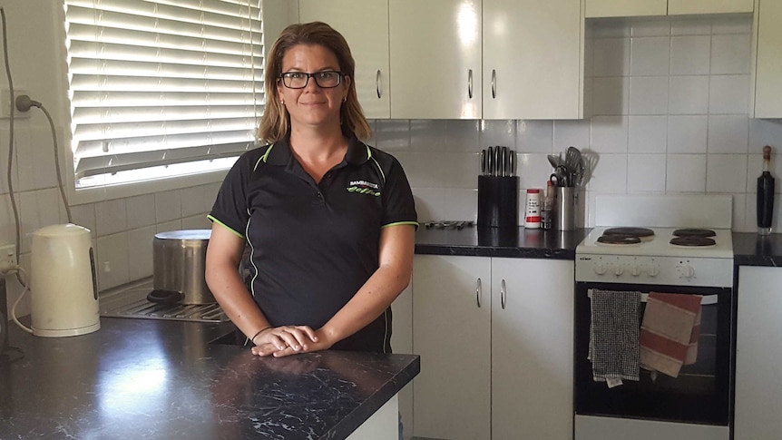 A mid-shot of Rockhampton resident Leticia Jukes standing in the kitchen of her home smiling and posing for a photo.