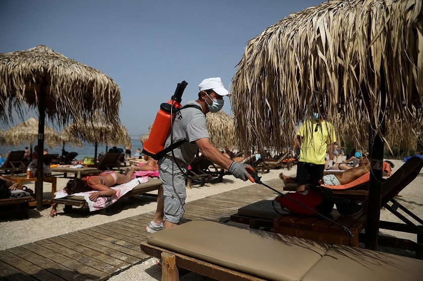 A man disinfects a sunbed during the official reopening of beaches to the public in Greece.