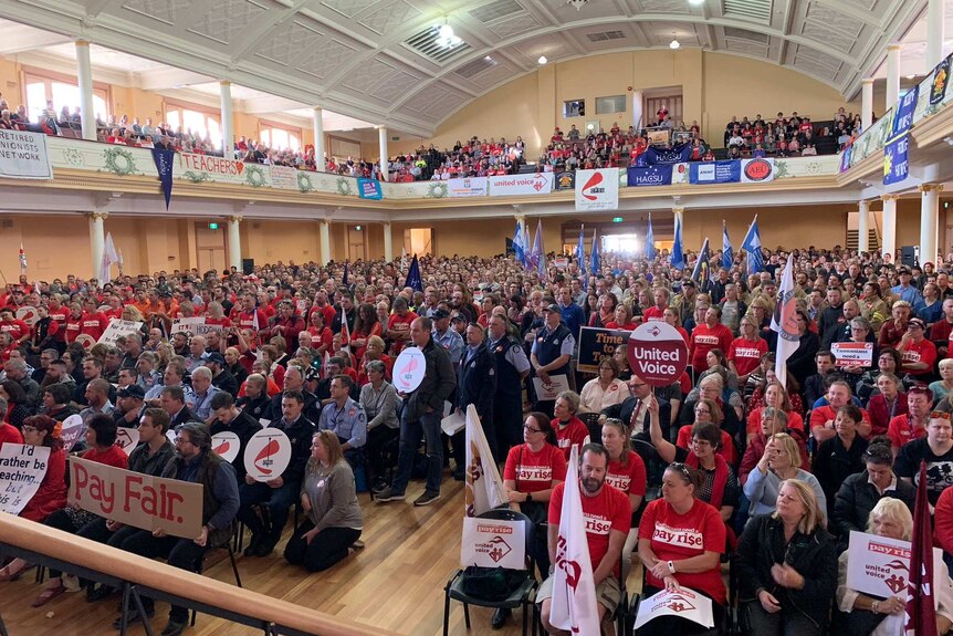 A packed hall filled with union workers with flags