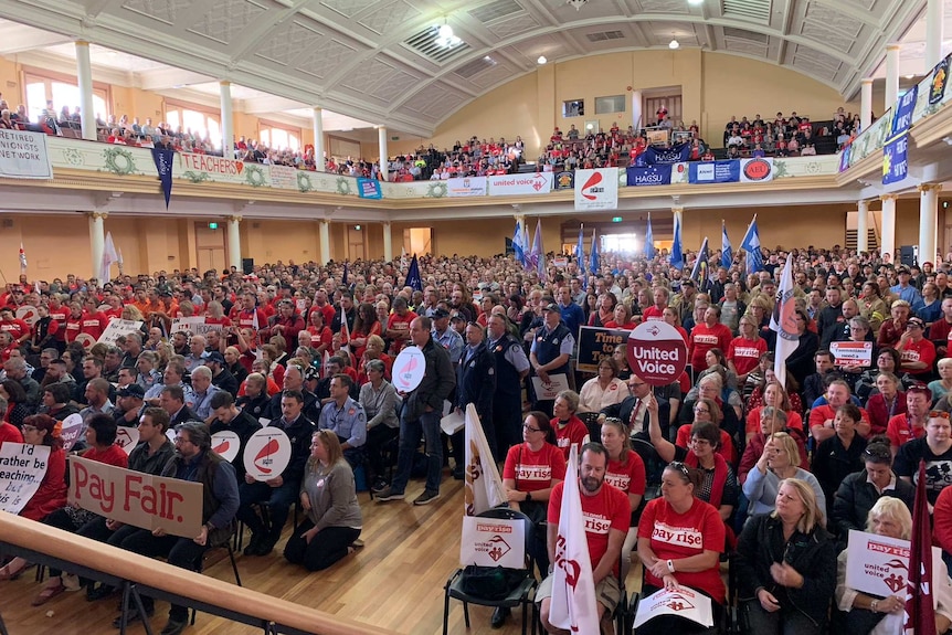 A packed hall filled with union workers with flags