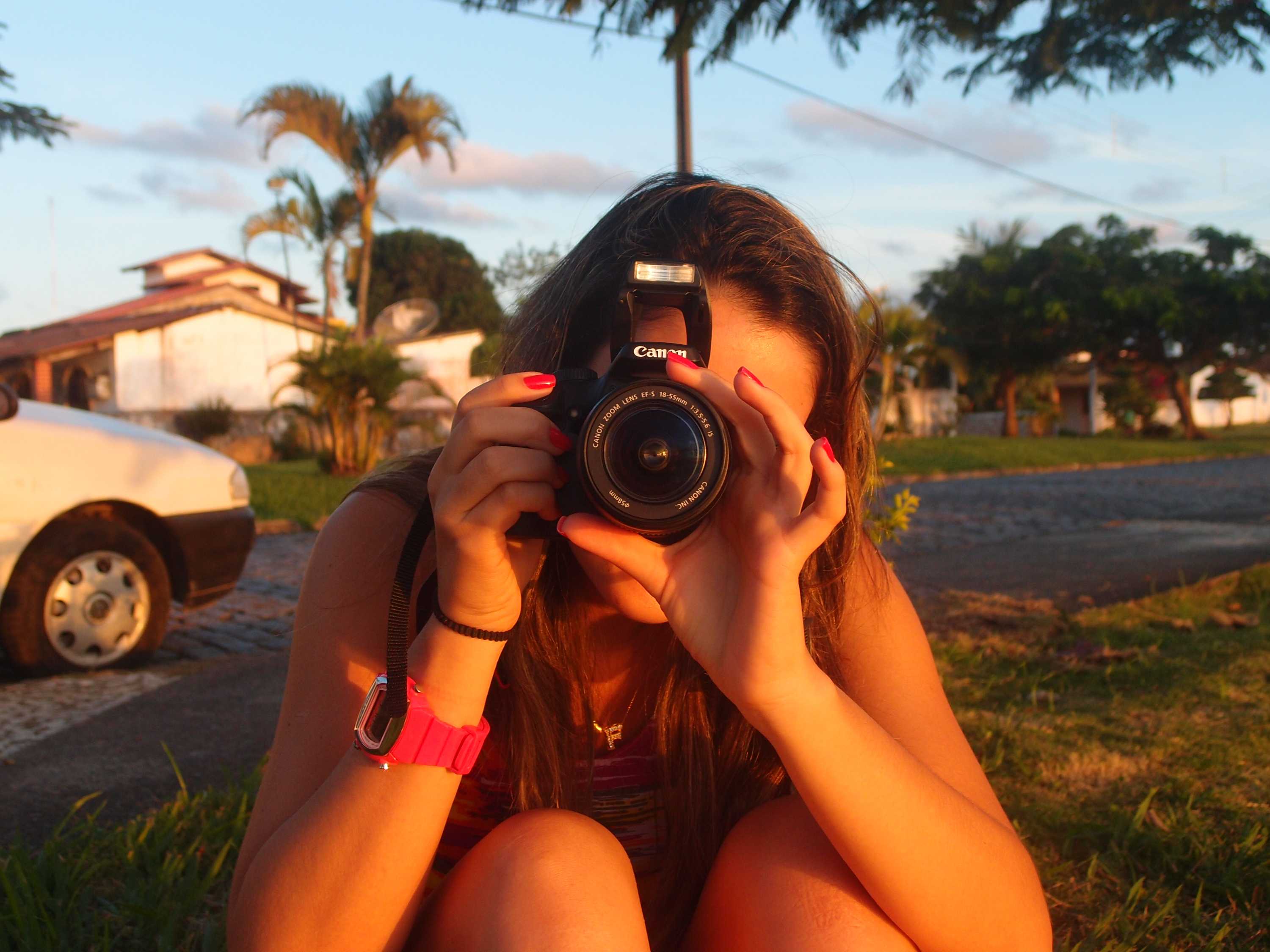 A woman holding a camera up to her face, taking a picture.