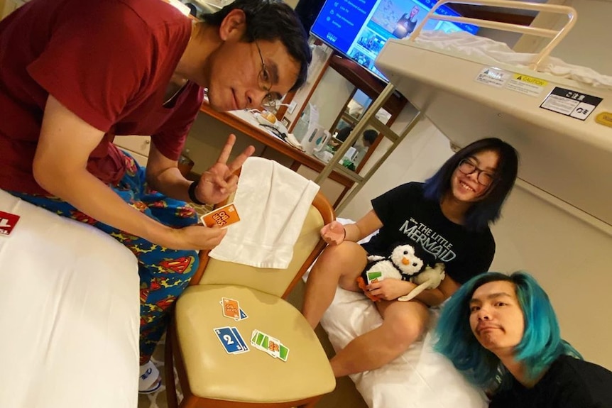 A family in a small windowless cabin playing cards