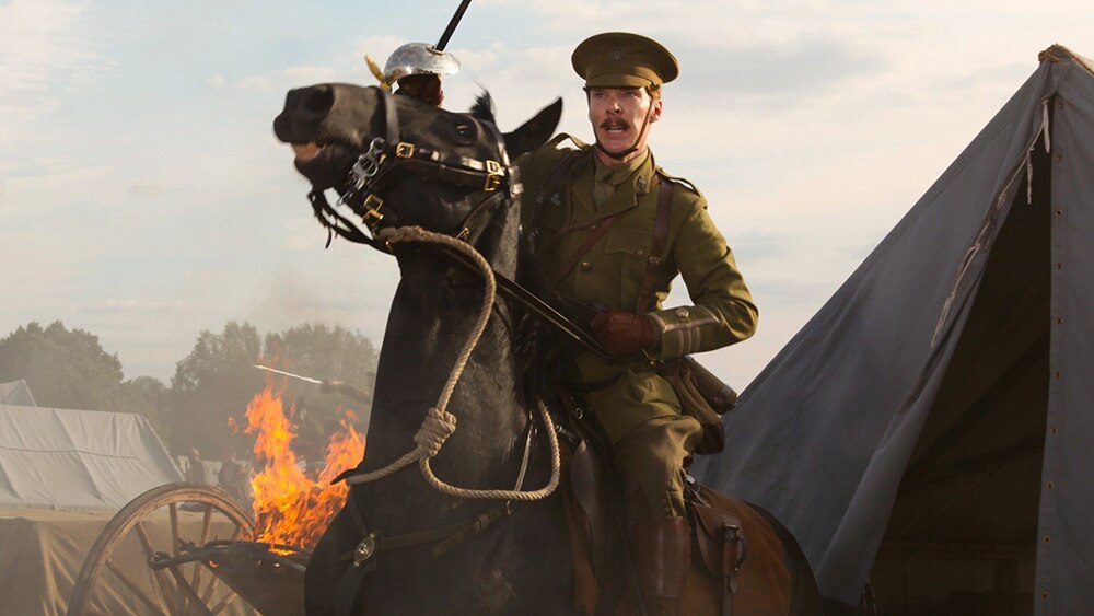 A moustached man in British allied colonel uniform sits atop a brown horse, pulling reins and with raised cavalry saber.