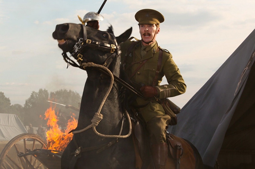 A moustached man in British allied colonel uniform sits atop a brown horse, pulling reins and with raised cavalry saber.
