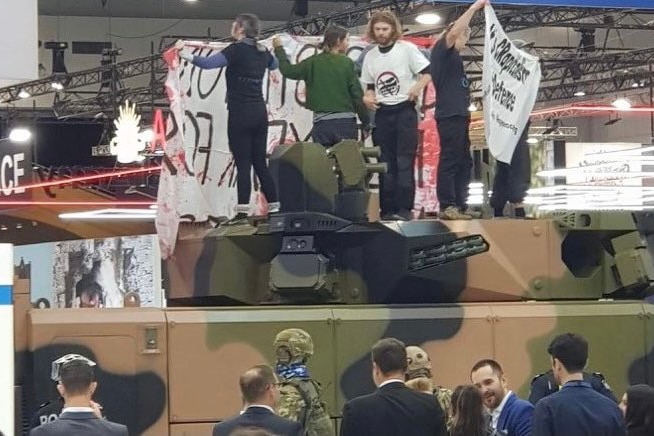Protesters on a tank at Brisbane's Land Forces Australia defence expo