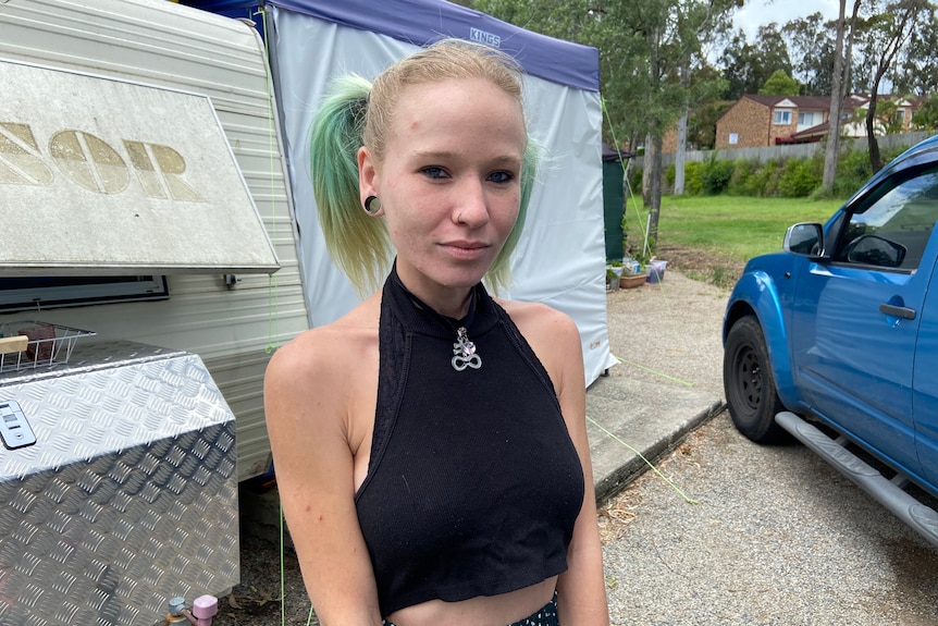 Shae Hilton stands outside a caravan