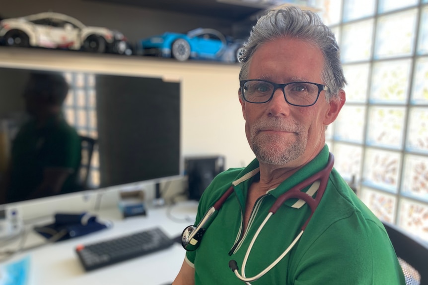 A doctor in a green polo shirt looking at the camera