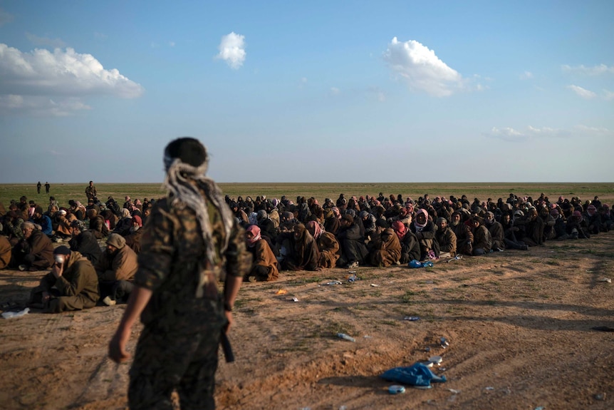 Groups of men sitting on the ground in the desert