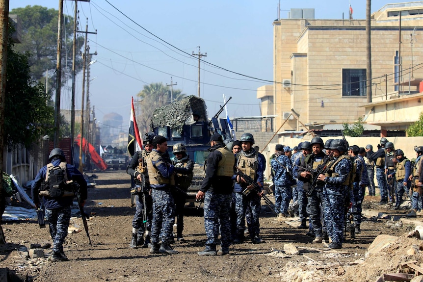 Federal police members carry their weapons in Dawasa near the main government complex.