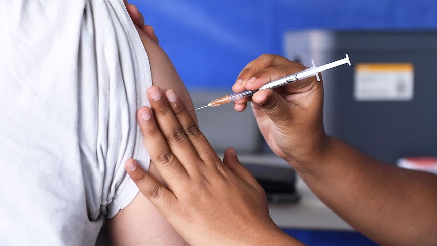 A person gets a vaccination in their right arm by a nurse.