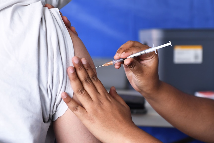 A person gets a vaccination in their right arm by a nurse.