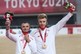 Two Polish male track cyclists stand on the medal podium at the Tokyo Paralympics.