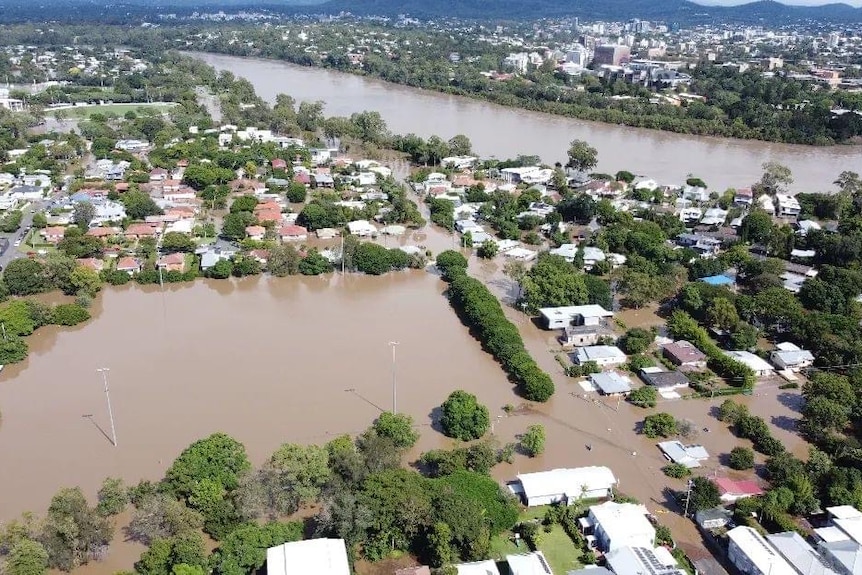 An aerial view of houses flooded by brown water.