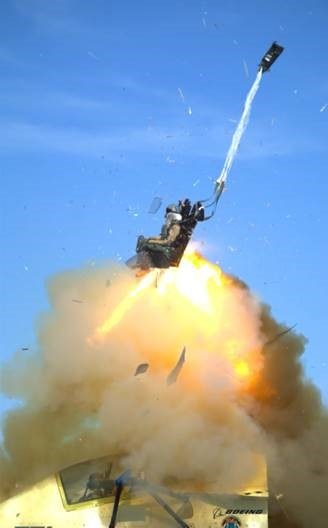 A dummy being blasted from a jet in an ejection chair with a small parachute deploying overhead.