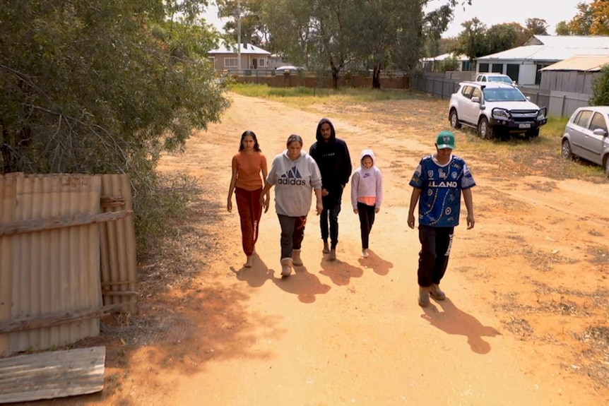 Drone shot of indigenous family working on a dusty street.