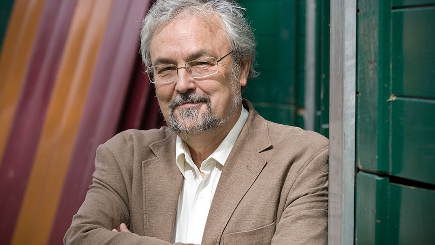 Robin Dunbar stands with arms crossed in front of striped wall