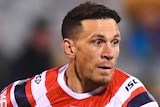 A Sydney Roosters NRL player holds the ball in two hands as he prepares to throw a pass against the Canberra Raiders.