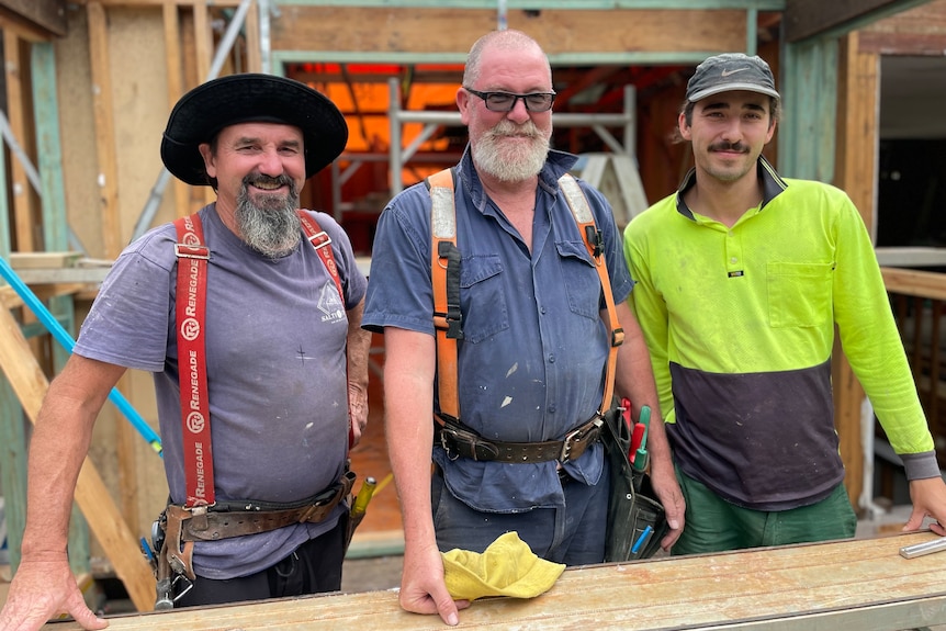 three builders at a house construction site