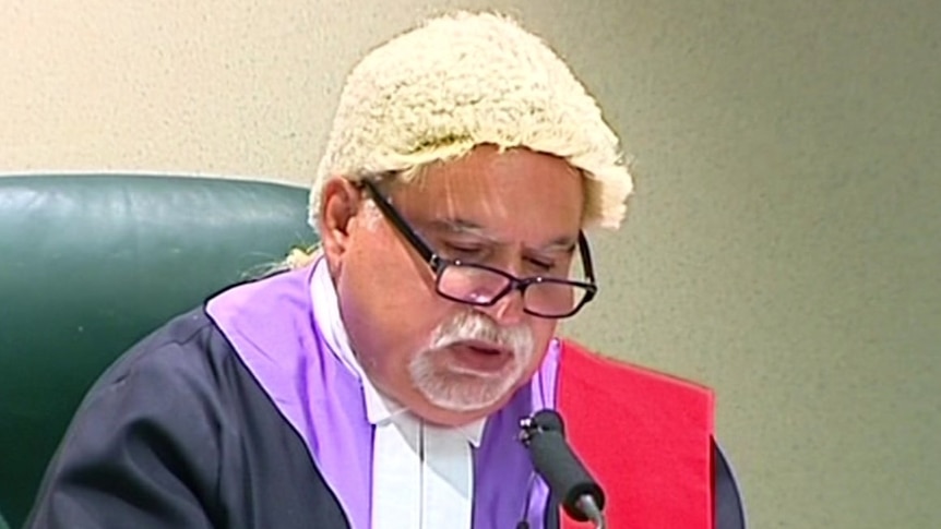 A man with glasses in a judge's wig 