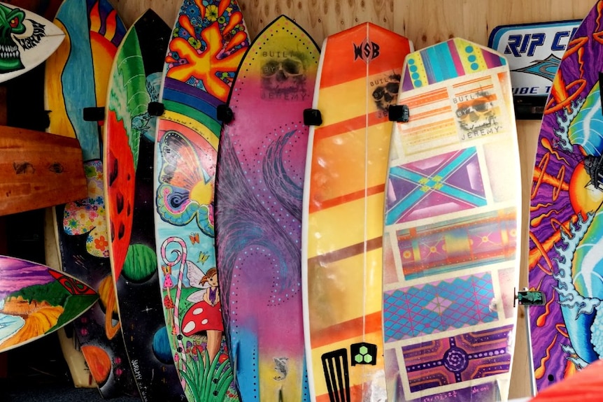 Six colourful boards painted by Jeremy Ievins lined up next to each other in his shed