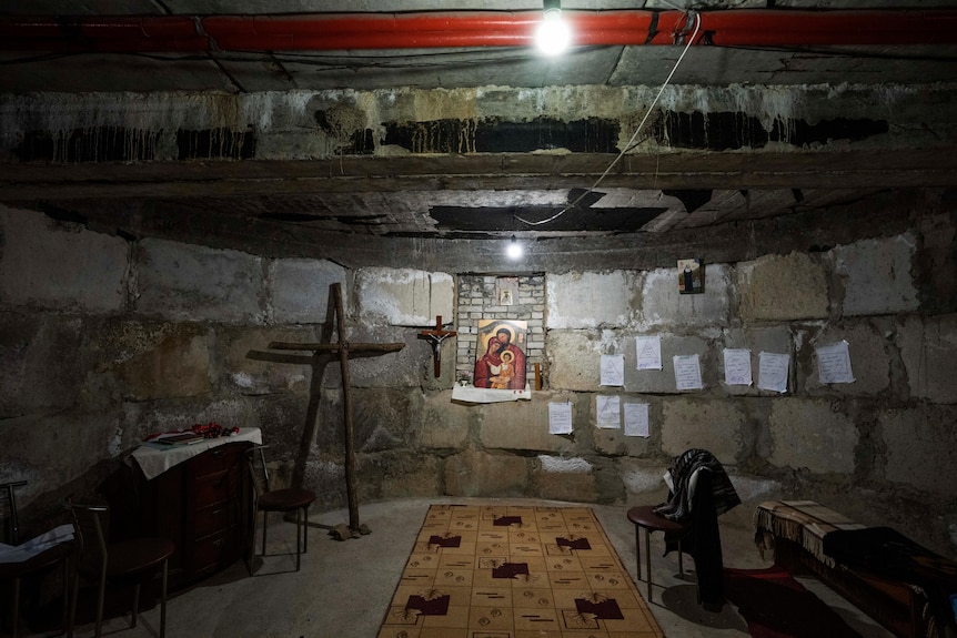 A makeshift chapel set up in a basement, with large crucifixes and a religious painting on the wall.