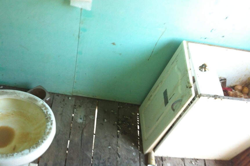 A filthy toilet and sink in a bathroom of a backpacker property