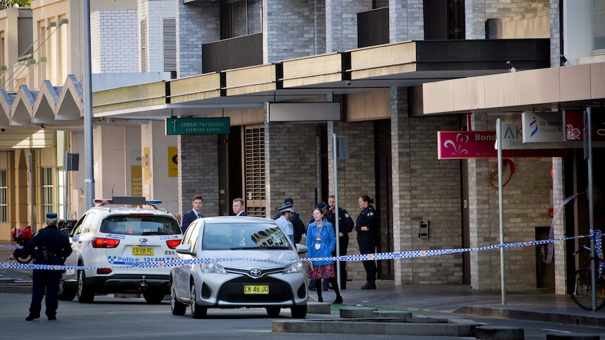 Police officers and cars outside building with police tape