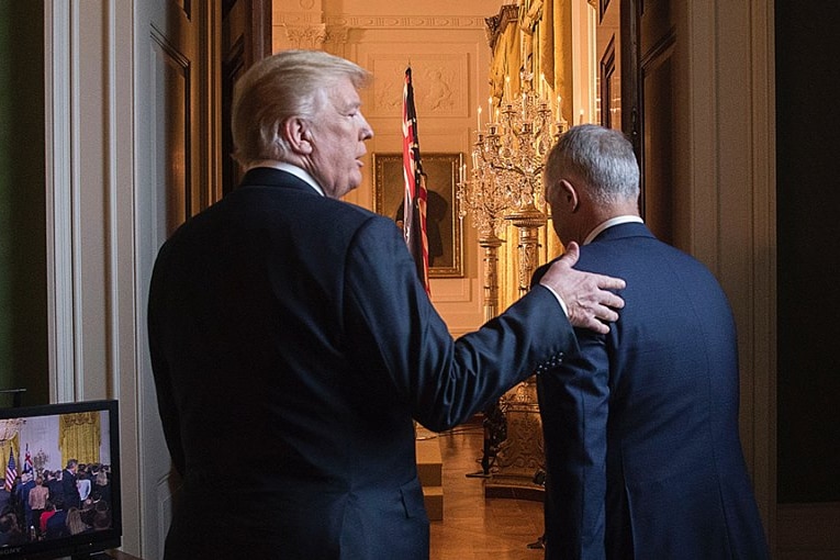 Donald Trump pats Malcolm Turnbull on the back as they walk through a door.