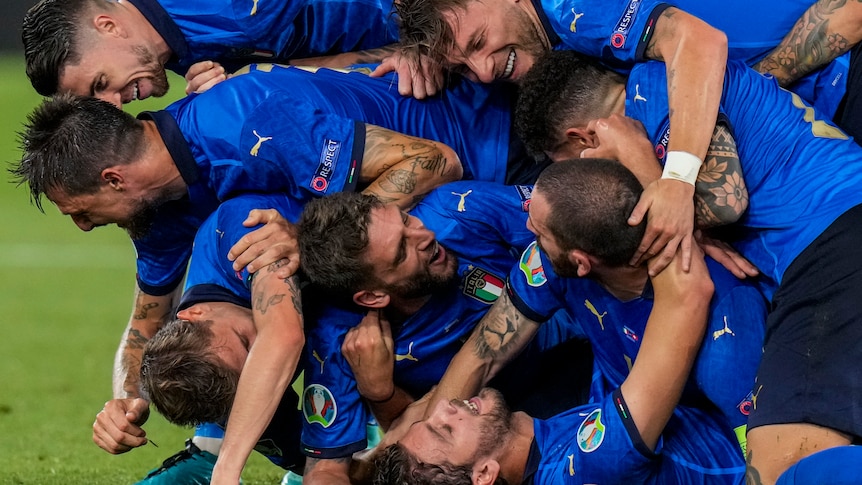 A number of Italian players form a human pile as they celebrate a goal.