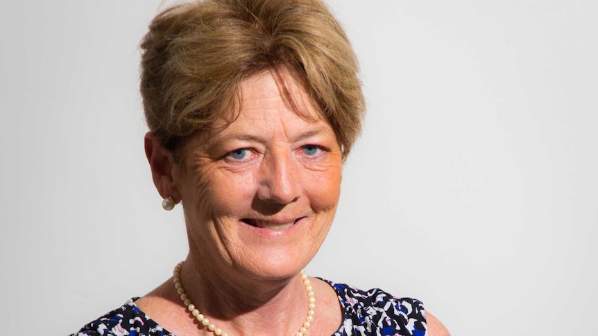 A portrait shot of a smiling middle-aged woman with short, light hair.