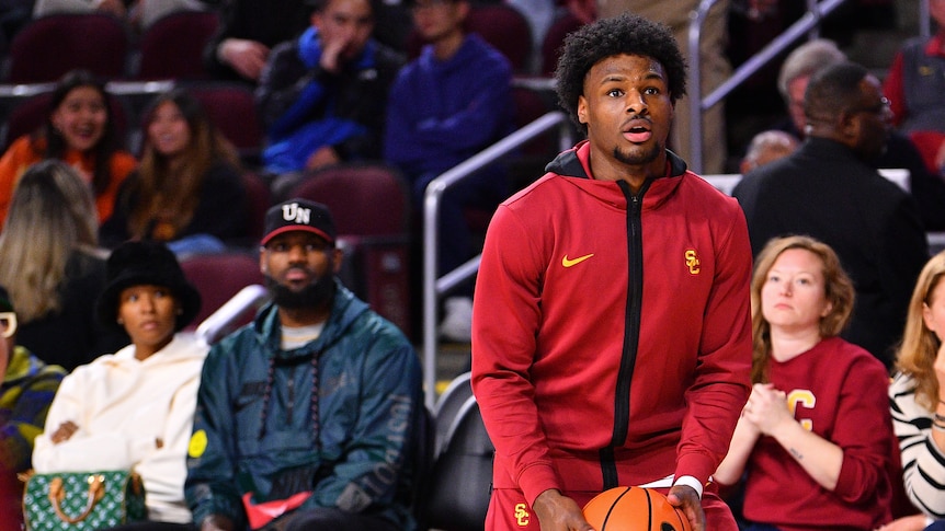 USC player Bronny James warms up for a college basketball in front of father and NBA star LeBron James.
