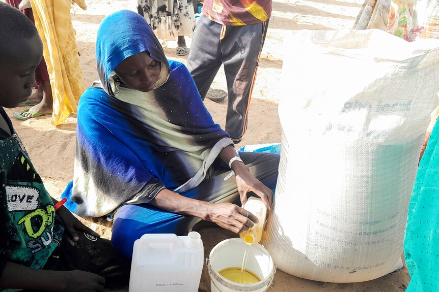 Amne Moustapha a pregnant Sudanese refugee sits in front of a food package in Chad.