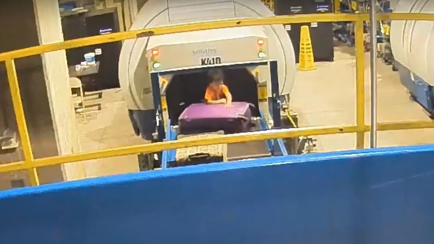 A toddler stuck on a conveyor belt tries to climb over luggage to get away from a baggage screening machine at Atlanta airport.