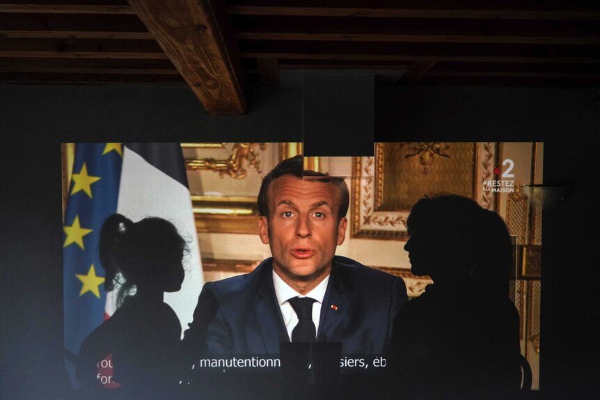 A family watches French President Emmanuel Macron's televised speech.