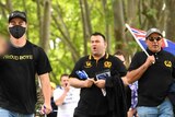 Men in black tops with the Proud Boys name and logo walk down St Kilda Road.