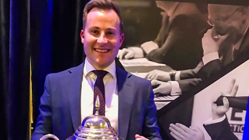 Auctioneer holds silver cup after being crowned number one.