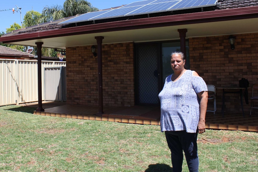 Sandra Riley standing out the front of her property with solar panels on the roof