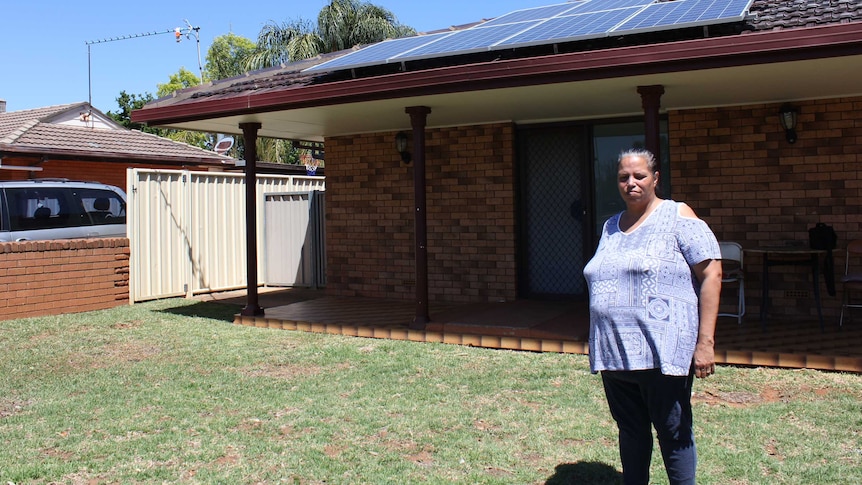 Sandra Riley standing out the front of her property with solar panels on the roof