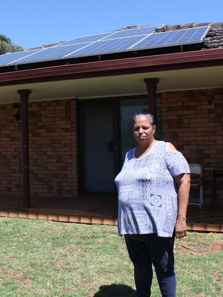 Sandra Riley standing out the front of her property with solar panels on the roof