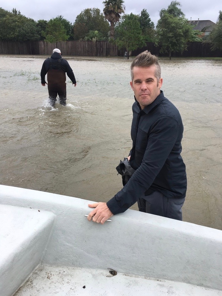 Duffy knee deep in water as man in waders walks through floods in background.