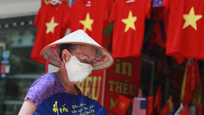 A woman walks past a row of T-shirts printed with Vietnamese flags in Hanoi.