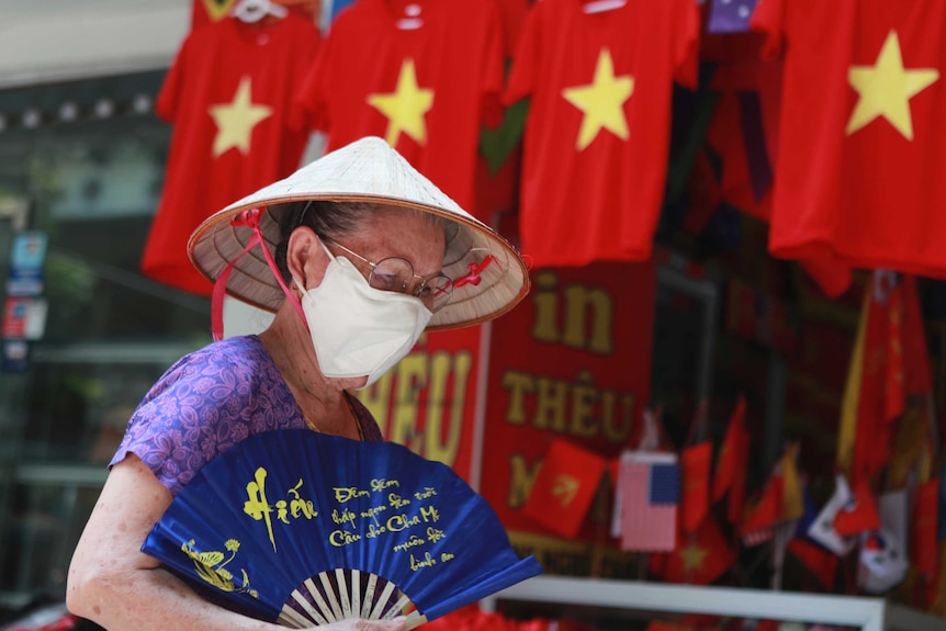 A woman walks past a row of T-shirts printed with Vietnamese flags in Hanoi.